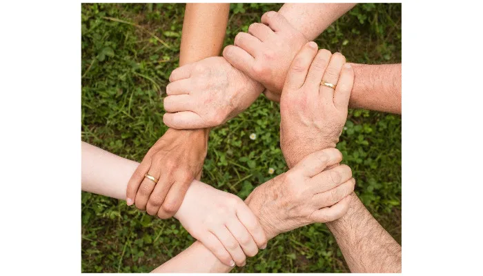 Sei persone che si prendono i polsi con le mani per formare un cerchio